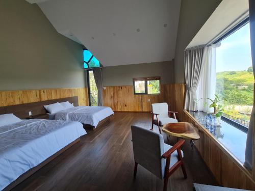 een slaapkamer met 2 bedden, een tafel en een raam bij THẢO NGUYÊN VILLA BẢO LỘC in B'su M'rac