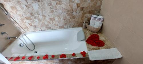 y baño con bañera con rosas rojas en el suelo. en Cabaña Rodamonte - Neusa, en Cogua