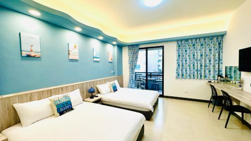 um quarto de hotel com duas camas e uma secretária em 澎湖凱悅輕旅電梯民宿 em Magong
