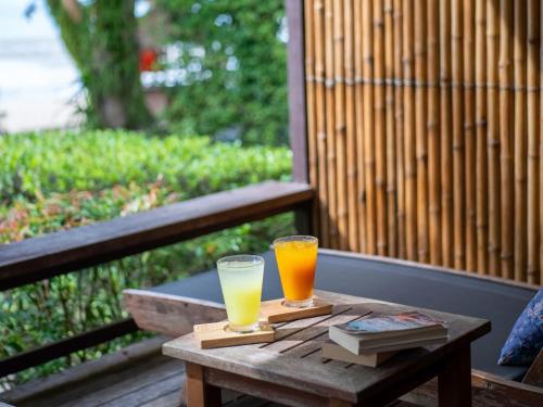 two glasses of orange juice sitting on a wooden table at Tup Kaek Sunset Beach Resort-SHA Plus in Tab Kaek Beach