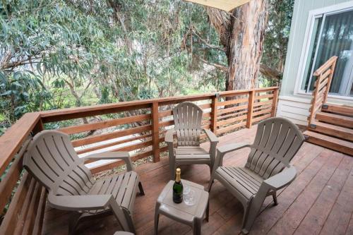 three chairs and a bottle of wine on a deck at Peaceful Tiny Home Loft and Sauna in San Luis Obispo