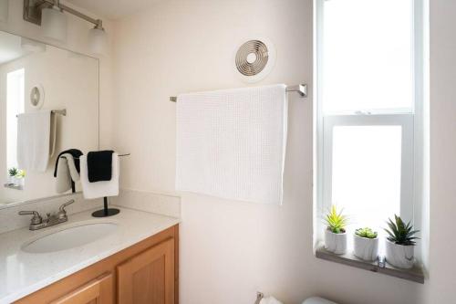a white bathroom with a sink and a mirror at Peaceful Tiny Home with Two Queens and Loft in San Luis Obispo