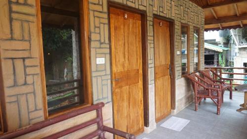 a porch with wooden doors and chairs on a building at Rain Forest Guest House and Jungle Trekking in Bukit Lawang