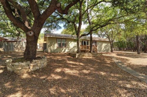 una casa con un árbol en el patio en The Hideout at Hills Haven, en Wimberley