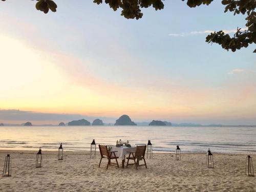 a table and chairs on a beach with the ocean at Tup Kaek Sunset Beach Resort-SHA Plus in Tab Kaek Beach