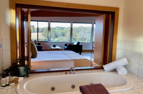 um quarto com uma cama e uma banheira num quarto em Hilltop Studios em Margaret River
