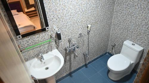 a bathroom with a sink and a toilet and a mirror at Hotel Maisha International in Sonāmura