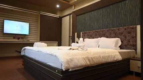 a bedroom with a large bed and a flat screen tv at Hotel Maisha International in Sonāmura