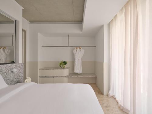 a white bedroom with a bed and a mirror at Ardo in Townsville