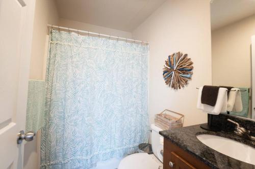 a bathroom with a blue shower curtain and a toilet at 2-Bedroom SLO Bungalow House in San Luis Obispo