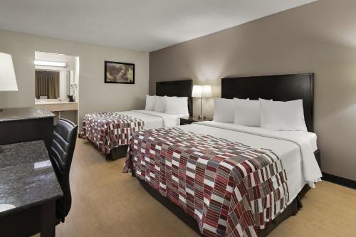 a hotel room with two beds and a desk at Red Roof Inn & Suites Cave City in Cave City