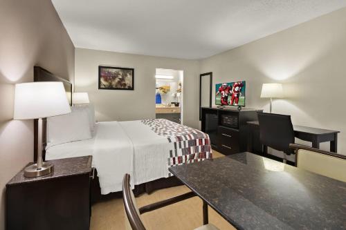 ケーブ・シティにあるレッド ルーフ イン＆スイーツ ケーブ シティのベッドとデスクが備わる小さなホテルルームです。