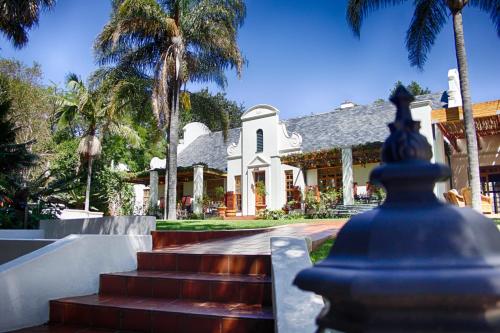 a house with palm trees and stairs in front of it at Kleine Constantia Boutique Guest House in Roodepoort