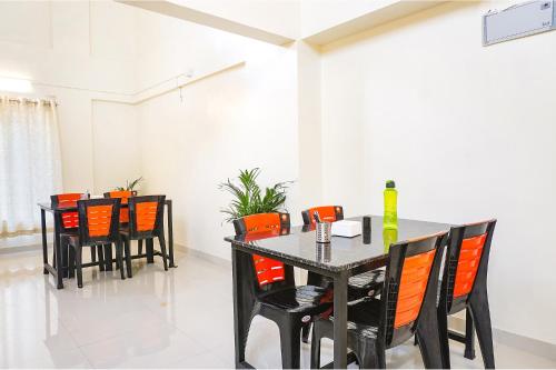 a dining room with a black table and orange chairs at FabHotel Majestic Luxurious - Nr Rajaram Bhiku Pathare Stadium in Pune