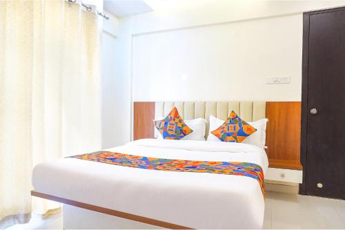 a bedroom with a large white bed with colorful pillows at FabHotel Majestic Luxurious in Pune