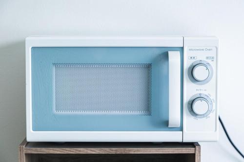 a microwave oven sitting on top of a wooden stand at 702 道頓堀側のお部屋 中心地へのアクセス抜群 ダブルベッド1台 in Osaka