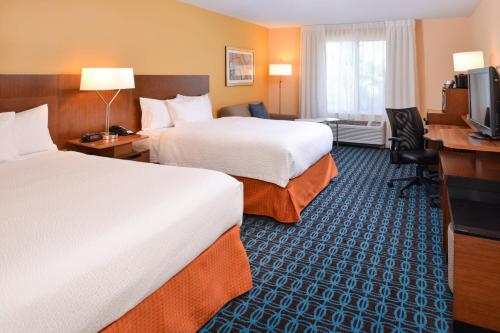 a hotel room with two beds and a desk at Fairfield Inn Orlando Airport in Orlando