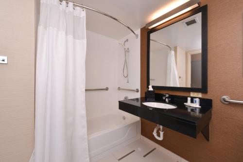 a bathroom with a sink and a tub and a mirror at Fairfield Inn Orlando Airport in Orlando