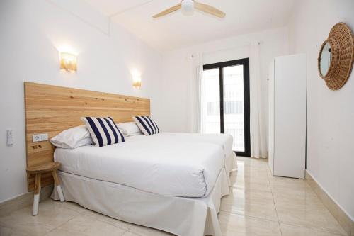a white bedroom with a large white bed with striped pillows at Hotel Casa Mas in Lloret de Mar