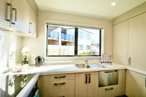 a kitchen with a sink and a window at Two-Bedroom House with Jacuzzi at Rototuna! in Hamilton