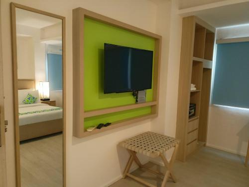 a room with a green wall with a tv on a wall at Lime Hotel Boracay in Boracay