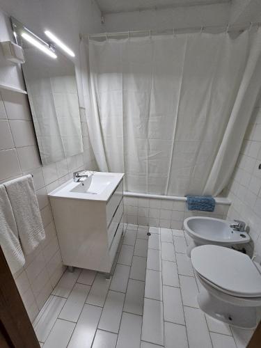 a white bathroom with a sink and a toilet at Romeu in Quarteira