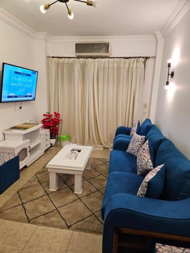 salon z niebieską kanapą i telewizorem w obiekcie شقة مفروشةومريحةفي مدينتي قريبة من كل الخدمات والحركة w mieście Madinaty