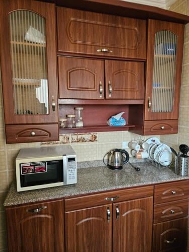 kuchnia z drewnianymi szafkami i kuchenką mikrofalową na ladzie w obiekcie شقة مفروشةومريحةفي مدينتي قريبة من كل الخدمات والحركة w mieście Madinaty