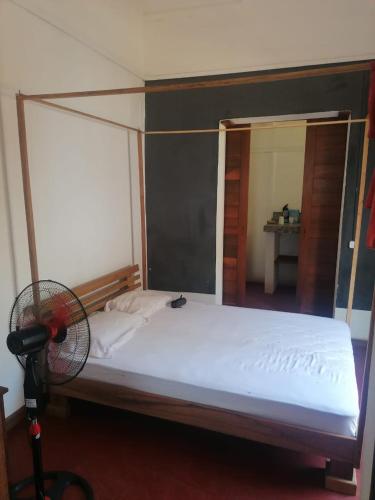 1 dormitorio con 1 cama con ventilador en Maison jaune bord de la mer, en Ambatoloaka