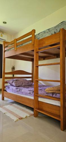 two bunk beds in a room with purple sheets at Pakin house in Ban Nua Khlong