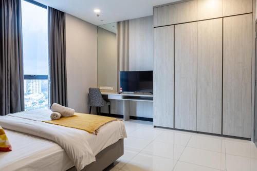 a bedroom with a bed and a desk and a tv at Societe Suites By iHost Global in Kuala Lumpur