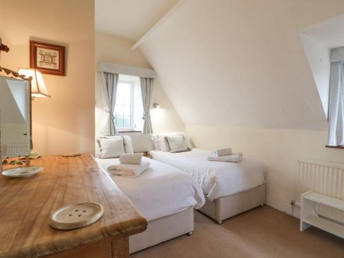 a bedroom with two beds and a wooden table at Cowfair Cottage in Chipping Campden