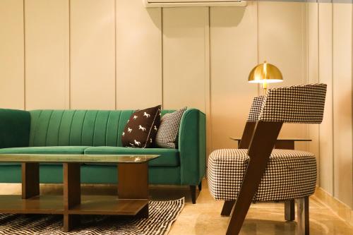 a living room with a green couch and a chair at Ahuja Residency Mayfield Garden in Gurgaon