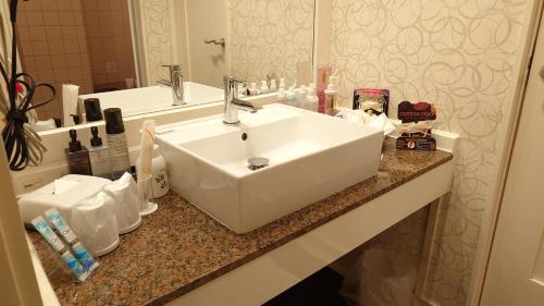 um balcão de casa de banho com um lavatório branco e um espelho em ホテルシエル静岡店 em Shizuoka