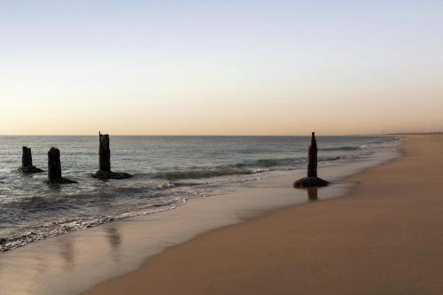 a beach with three posts in the water at Hawthorn Suites by Wyndham Dwarka in Dwarka