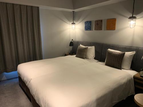 a bedroom with two beds with white sheets and pillows at Hotel Resol Akihabara in Tokyo