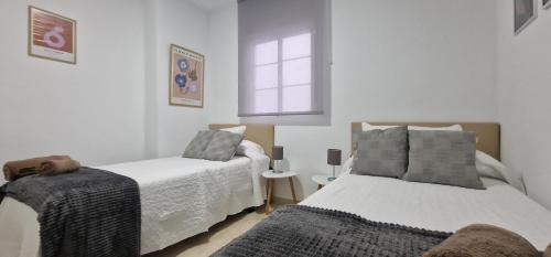 1 dormitorio con 2 camas y ventana en DS LealHomes, patio and terrace, en Córdoba