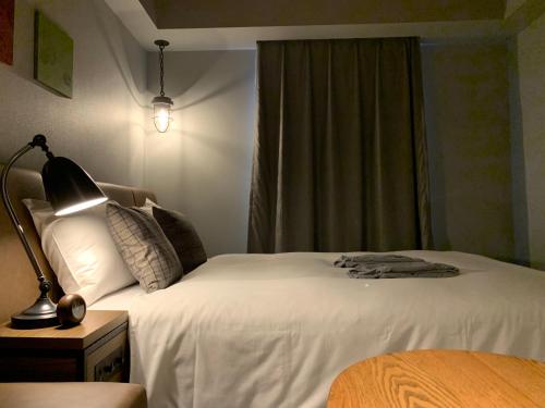 a bedroom with a bed and a lamp and a window at Hotel Resol Akihabara in Tokyo