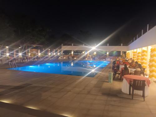 a group of people sitting around a table by a pool at night at Nilan Zingle Resort in Puducherry