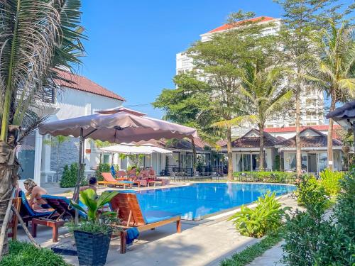 a pool at a resort with a woman sitting in a chair at Sea Breeze Resort in Sihanoukville