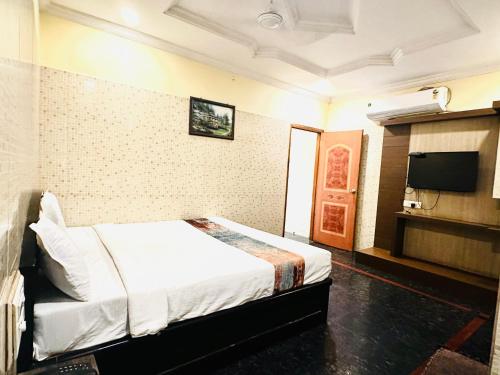 ein Hotelzimmer mit einem Bett und einem Flachbild-TV in der Unterkunft HOTEL TEJASRI RESIDENCY in Vijayawāda