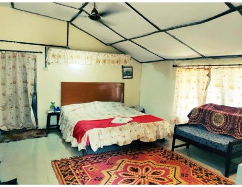 a bedroom with a large bed and a chair at Eve Resort, Pachmarhi in Pachmarhī
