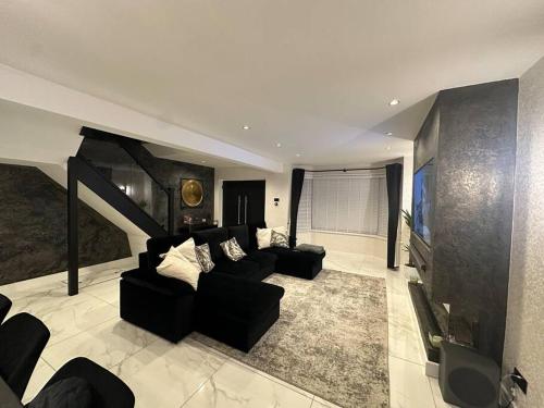 a living room with a black couch and a tv at Luxury 3 bed coastal house in North Tyneside