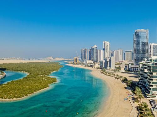 a view of a beach and a city with tall buildings at Waterfront Tropical Themed 2 BR in Abu Dhabi
