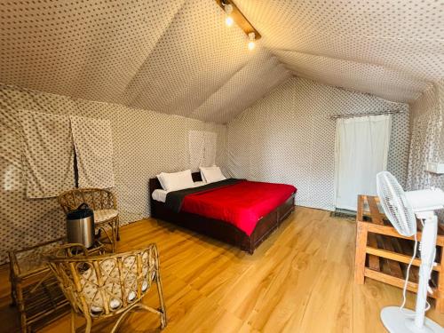 una camera da letto con letto rosso in mansarda di Room on the Roof, Viraatkhai-Chakrata, By Himalayan Eco Lodges a Chakrāta