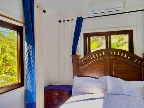 a bedroom with a wooden bed and a window at Roatan’s green view getaway. in Roatán