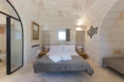 um quarto com uma cama e uma parede de pedra em Trullo Brenda. Originale e spettacolare em San Michele Salentino