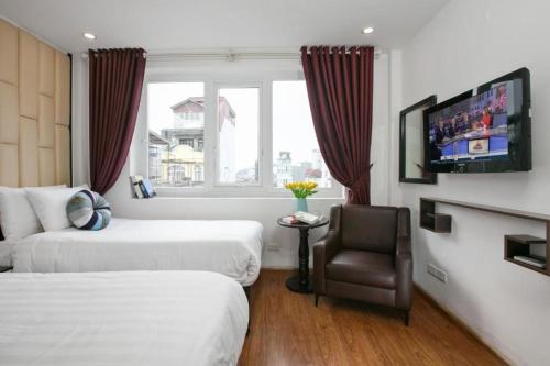 a hotel room with two beds and a chair at Splendid Holiday Hotel Spa in Hanoi