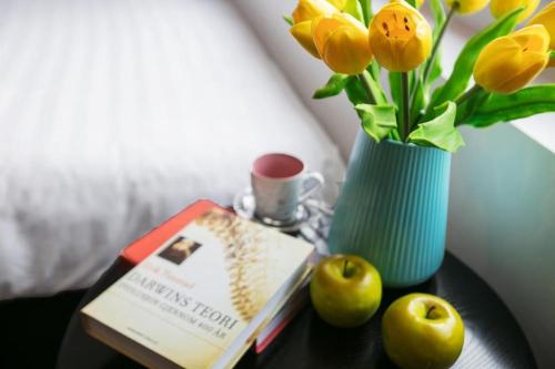 a table with a book and a vase with flowers at Splendid Holiday Hotel Spa in Hanoi