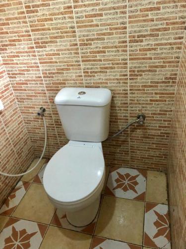 a bathroom with a white toilet in a brick wall at Tanzania Homestay in Arusha